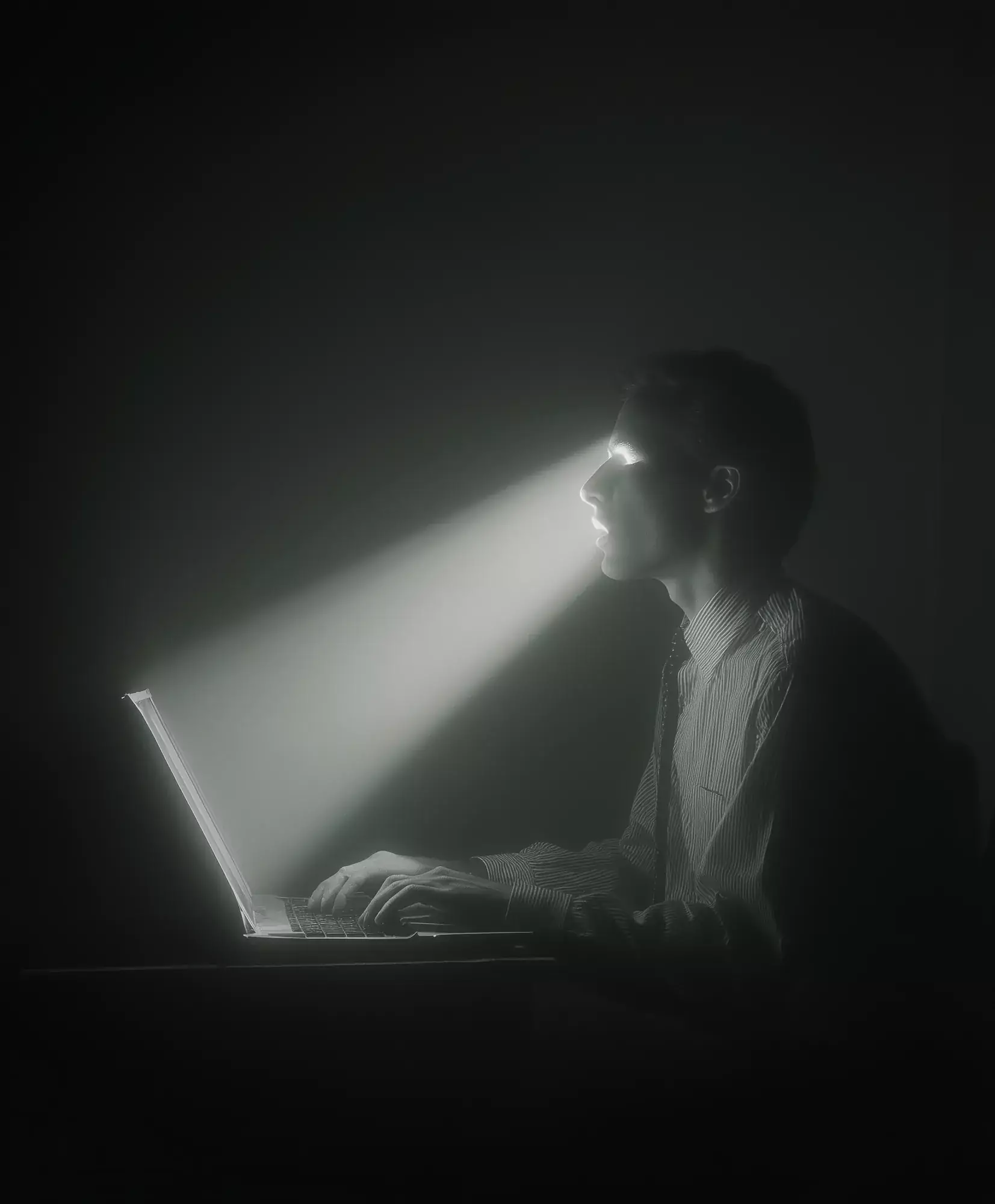 A person working at a laptop in a dark room