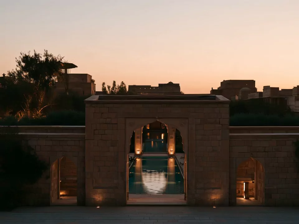 The stone gate house at dusk, the pool visible through its arch